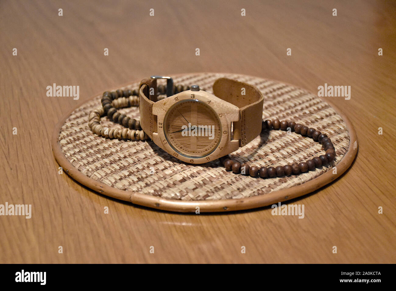 Eco-friendly, plastic-free and hand-made bamboo watch with leather strap from Thailand on a braided hemp plate surrounded by wooden bracelets on a woo Stock Photo