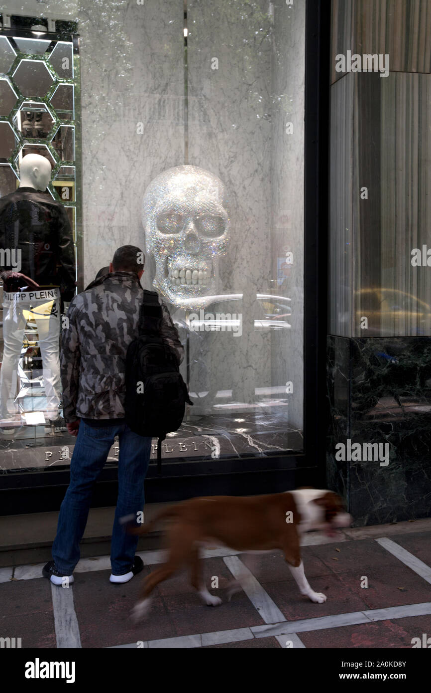 man and dog looking in shop window with skull stadiou athens attica greece Stock Photo