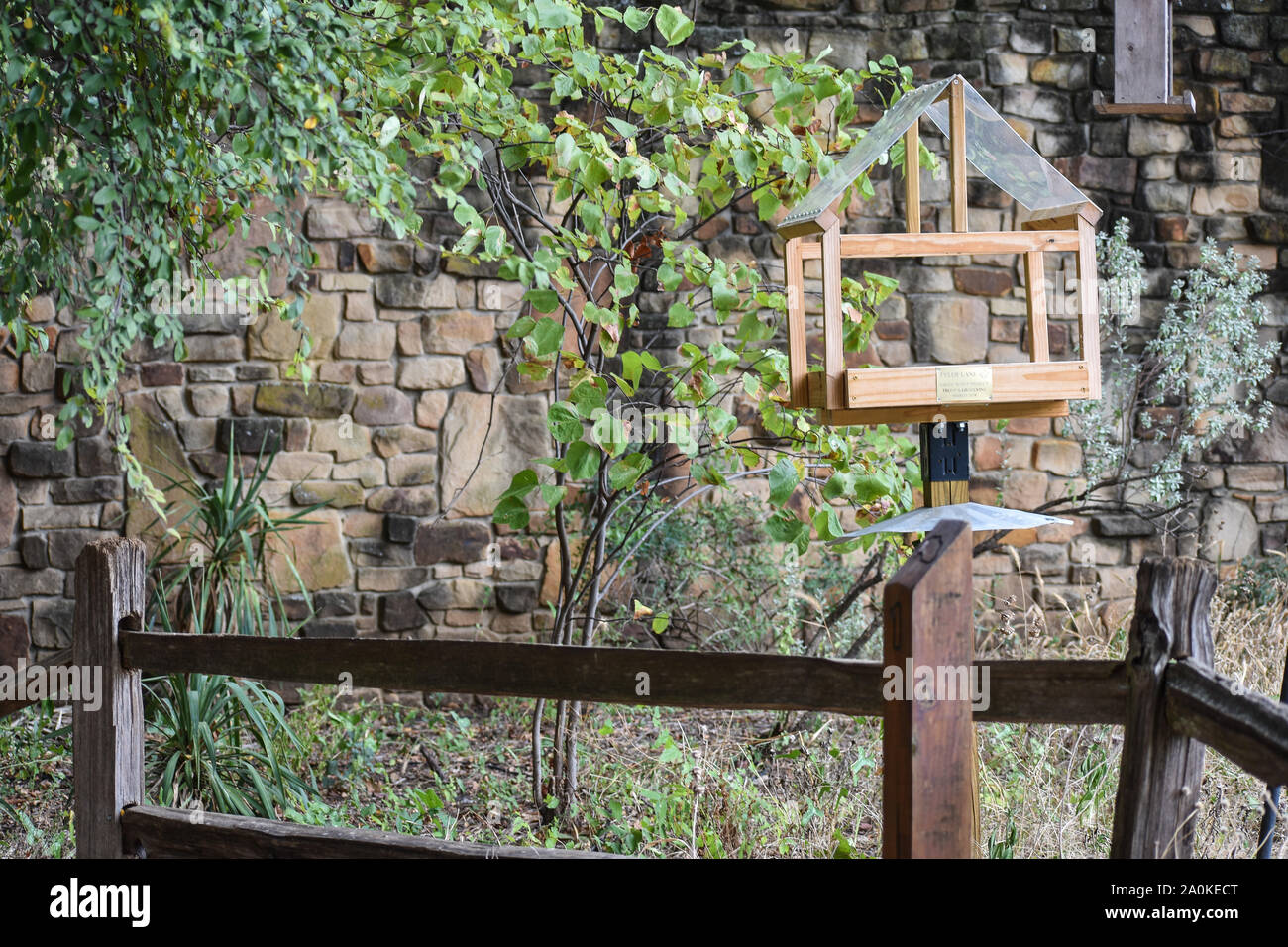 Pretty Natural Brick Wall With Bird Feeder And Fence Stock Photo