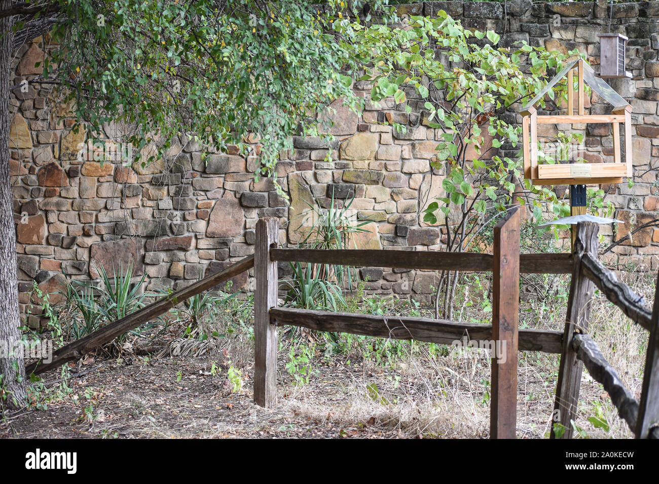 Pretty Natural Brick Wall With Bird Feeder And Fence Stock Photo
