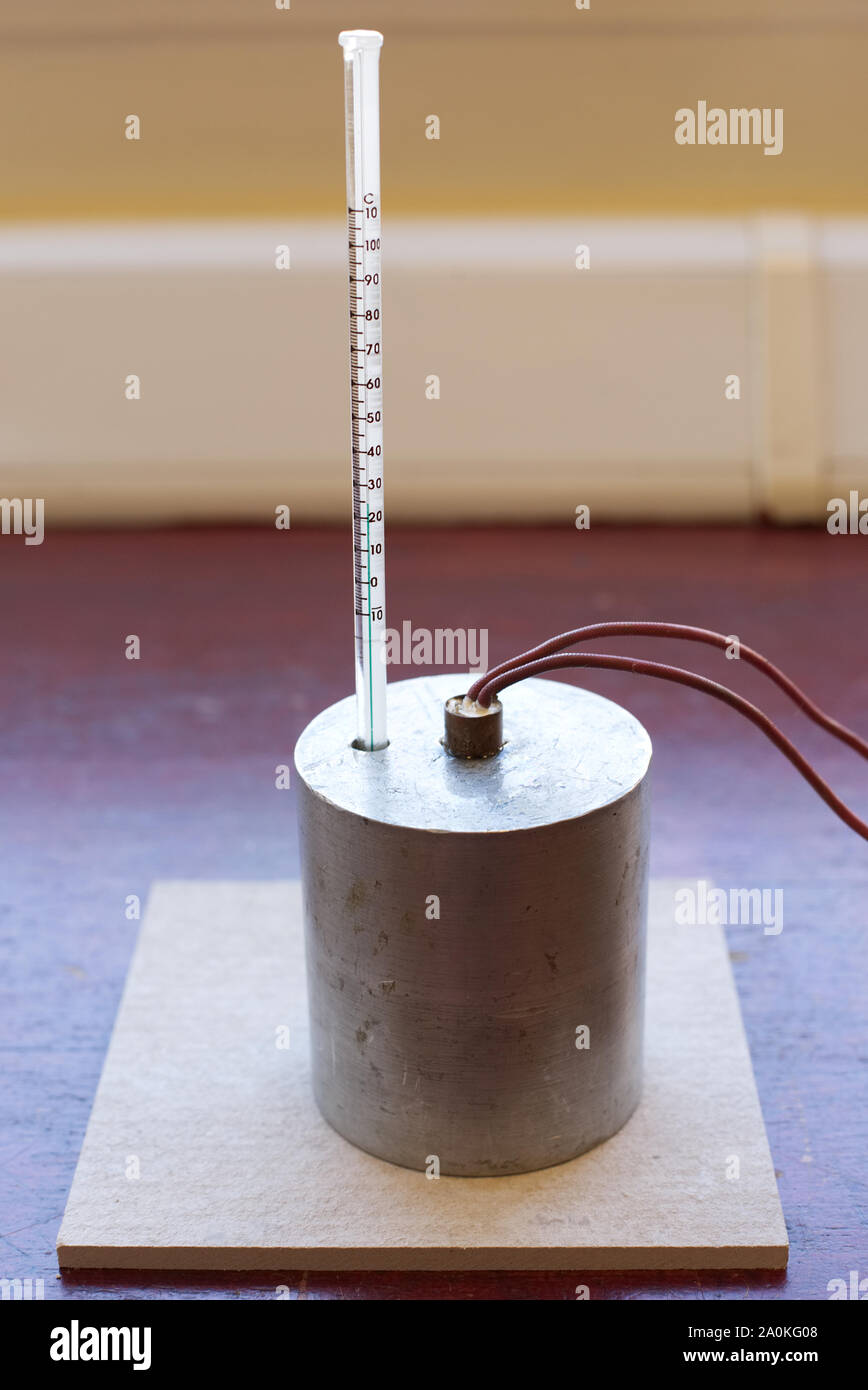 Specific Heat Capacity of Aluminium Experiment Set up with no insulation.  Aluminium block with an immersion heater and thermometer on a heatproof mat  Stock Photo - Alamy