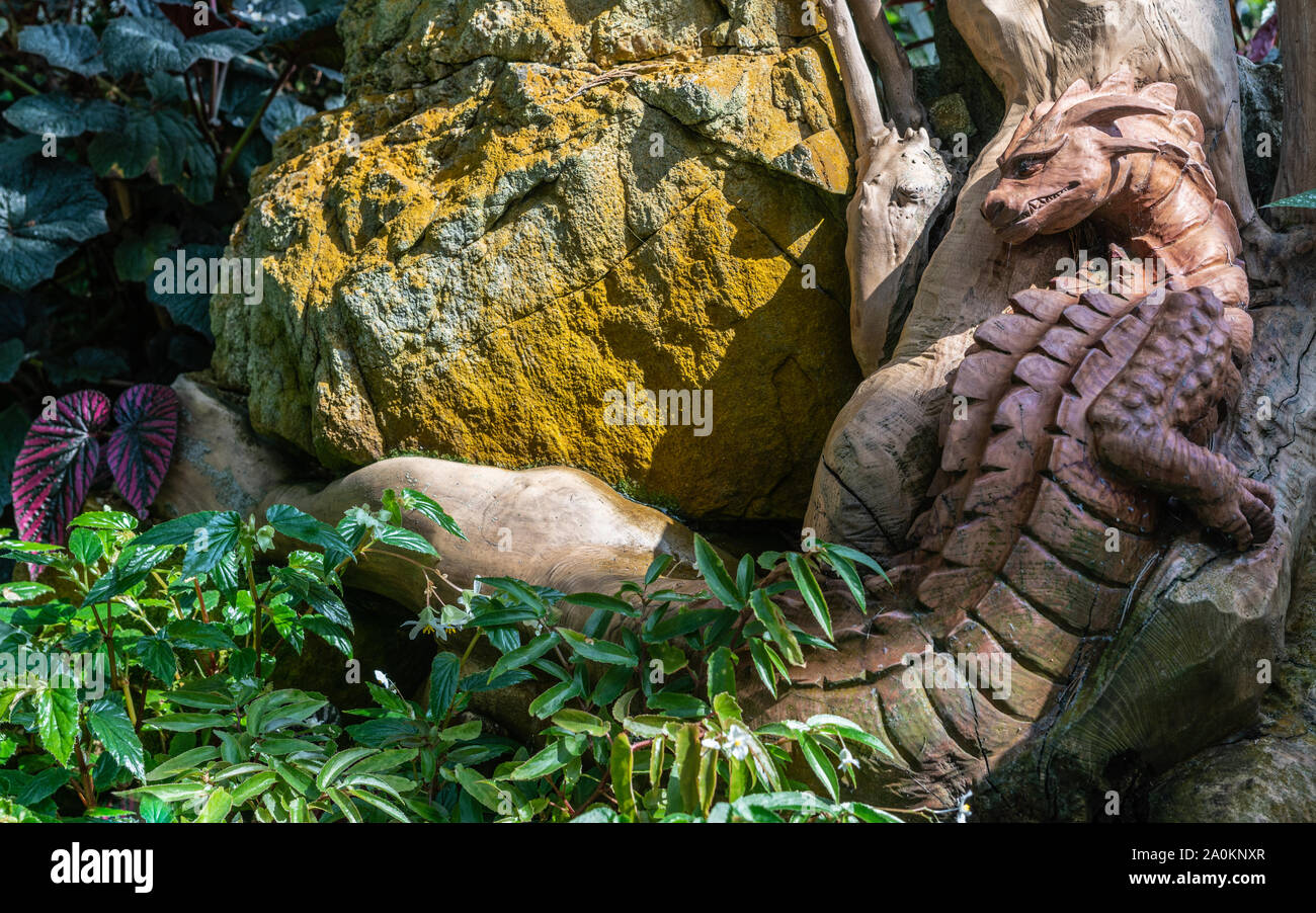 Singapore - March 22, 2019: Gardens by the Bay, the Cloud Forest Dome. Large brown wooden crocodile monster statue crawls through dense green vegetati Stock Photo