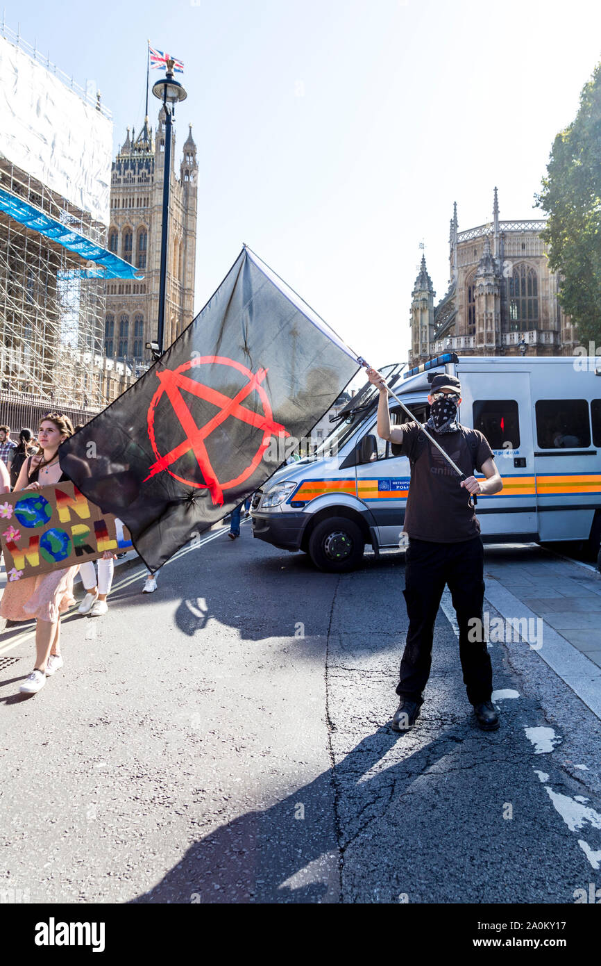 20 September 2019, London, UK - Man with face obscured by a scarf  holding an anarchy flag at the Global Climate Strike in Westminster Stock Photo