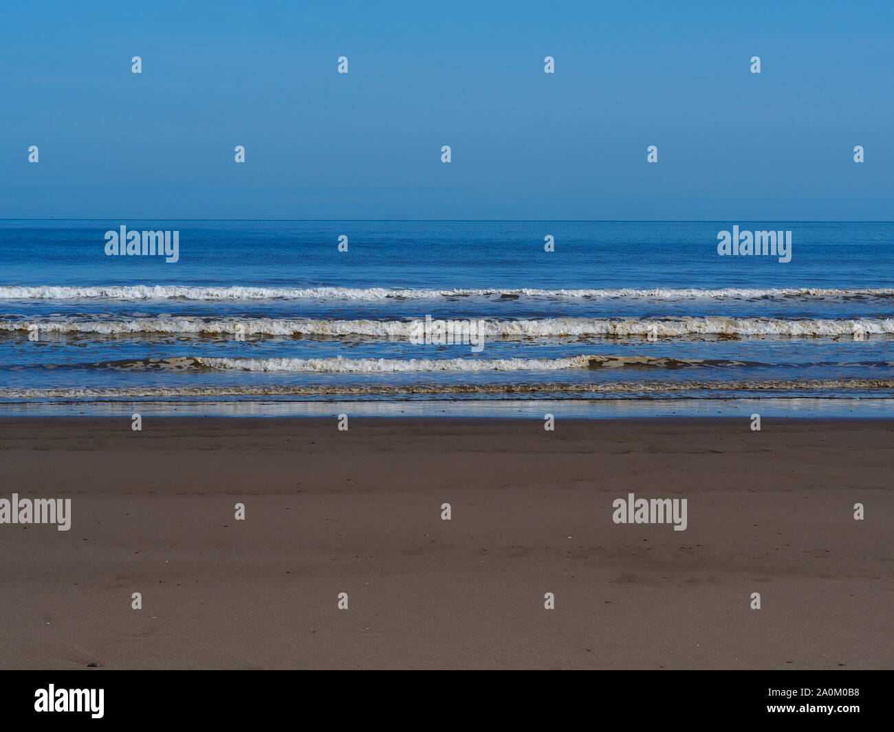 Waves with white surf approaching the sandy beach at Mablethorpe, Lincolnshire, England, on a beautiful summer day Stock Photo