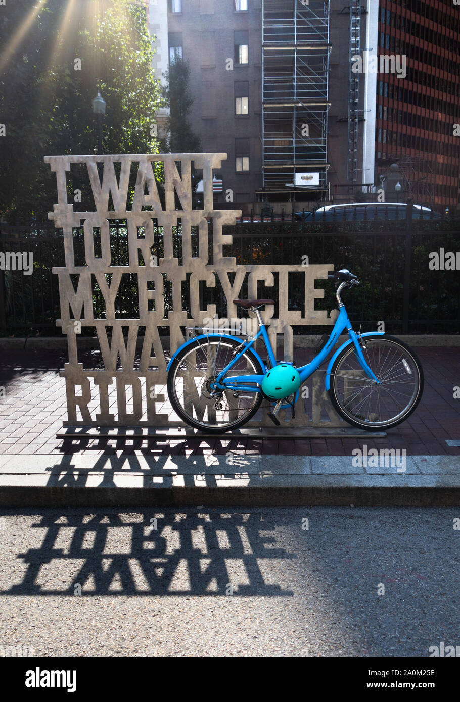 A cruiser style bicycle is chained to a bike rack that is a piece of metal art that says 'I want to ride by bicycle' in downtown Pittsburgh, PA, USA Stock Photo