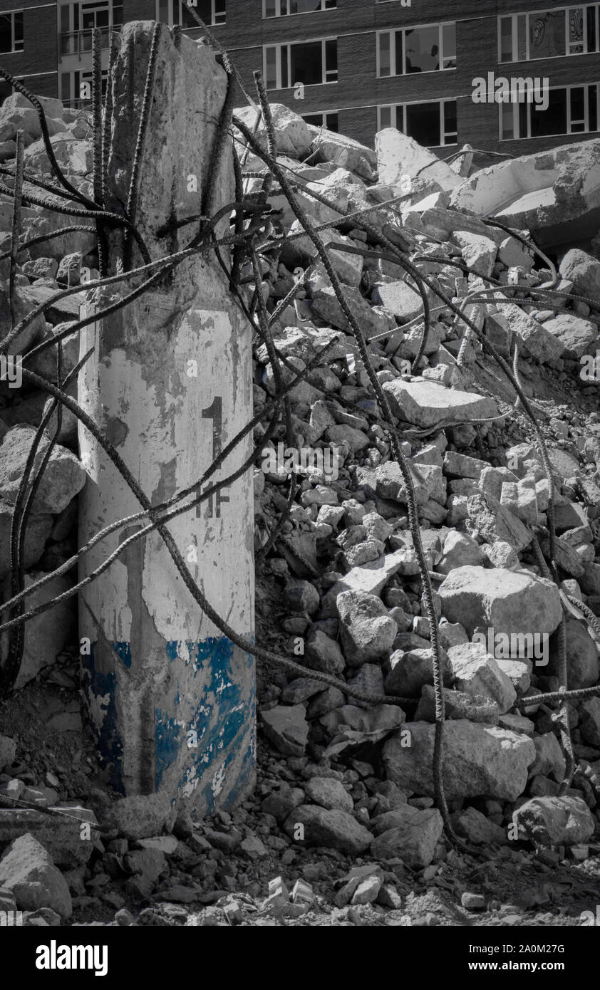 Rubble Standing Concrete pillar with exposed steel rebar standing amidst rubble and ...