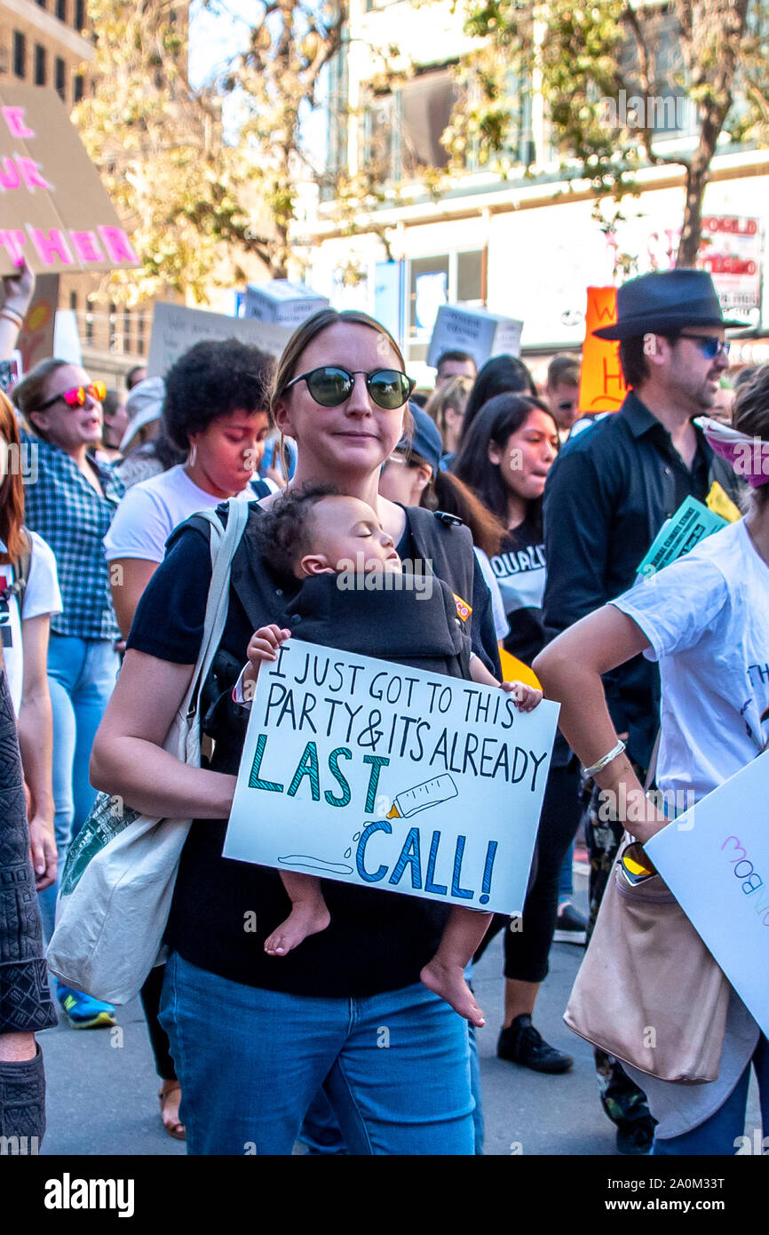 San Francisco, USA. 20th September, 2019. Student Strike for Climate march, one of many global climate strikes on this day around the world. A mother wears a baby in a front pack infant carrier with a sign reading, 'I just got to this party and it's already last call!' A baby bottle illustrates. Credit: Shelly Rivoli Stock Photo