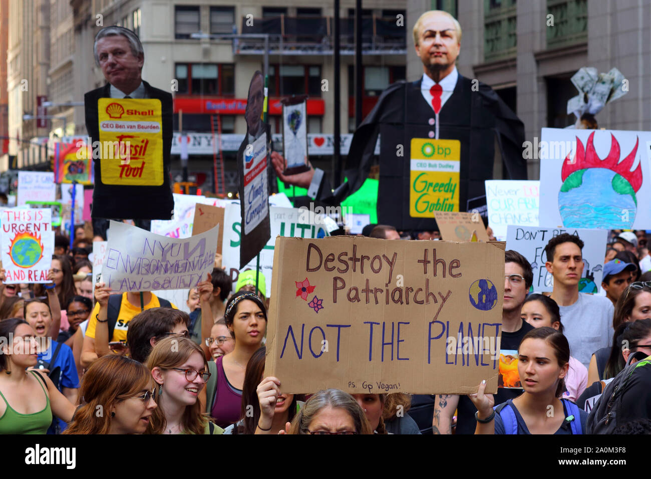 New York, NY. September 20, 2019. A person holds a sign 'Destroy the Patriarchy, Not the Planet' with effigies of energy company CEOs in the background at the youth-led NYC Climate Strike. Tens of thousands of people, students attended the march and rally down Broadway to Battery Park with Greta Thunberg as a participant and featured guest. Stock Photo