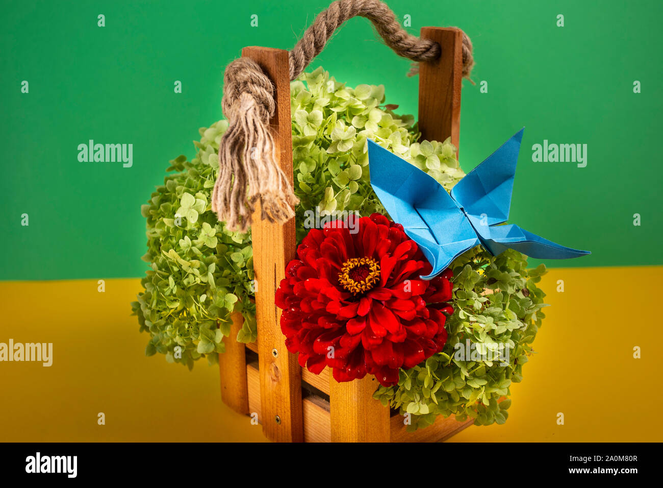origami butterfly crafted on a green bush in a basket on a colored background beautiful bouquet studio close shot Stock Photo