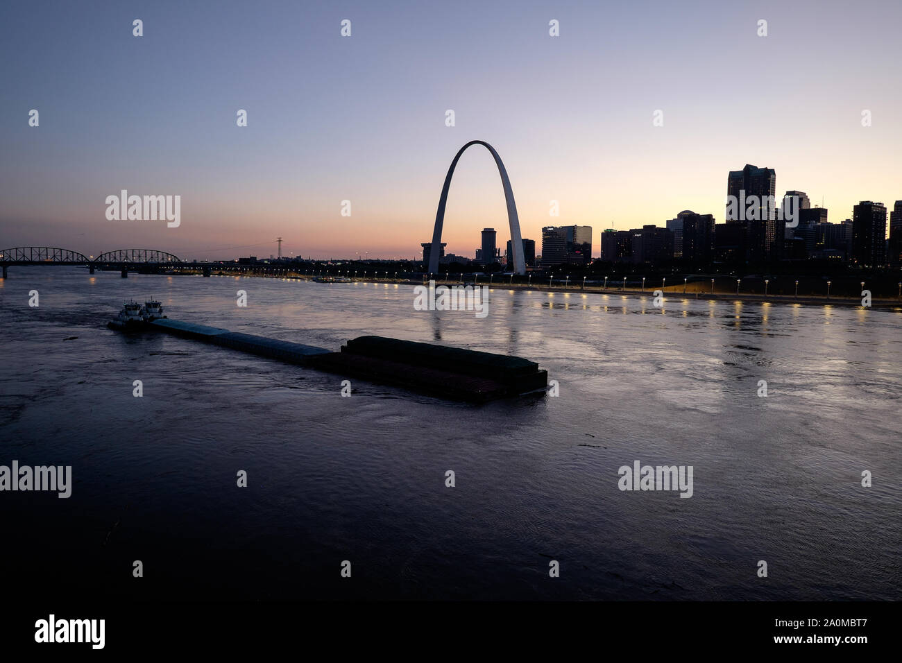 With the Gateway Arch standing out against a colorful sunset, the St. Louis skyline is seen over the Mississippi River Stock Photo