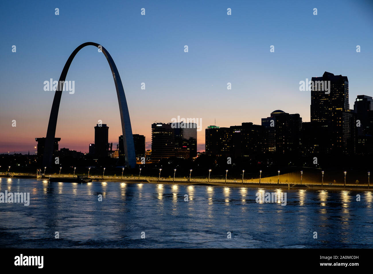 With the Gateway Arch standing out against a colorful sunset, the St. Louis skyline is seen over the Mississippi River Stock Photo