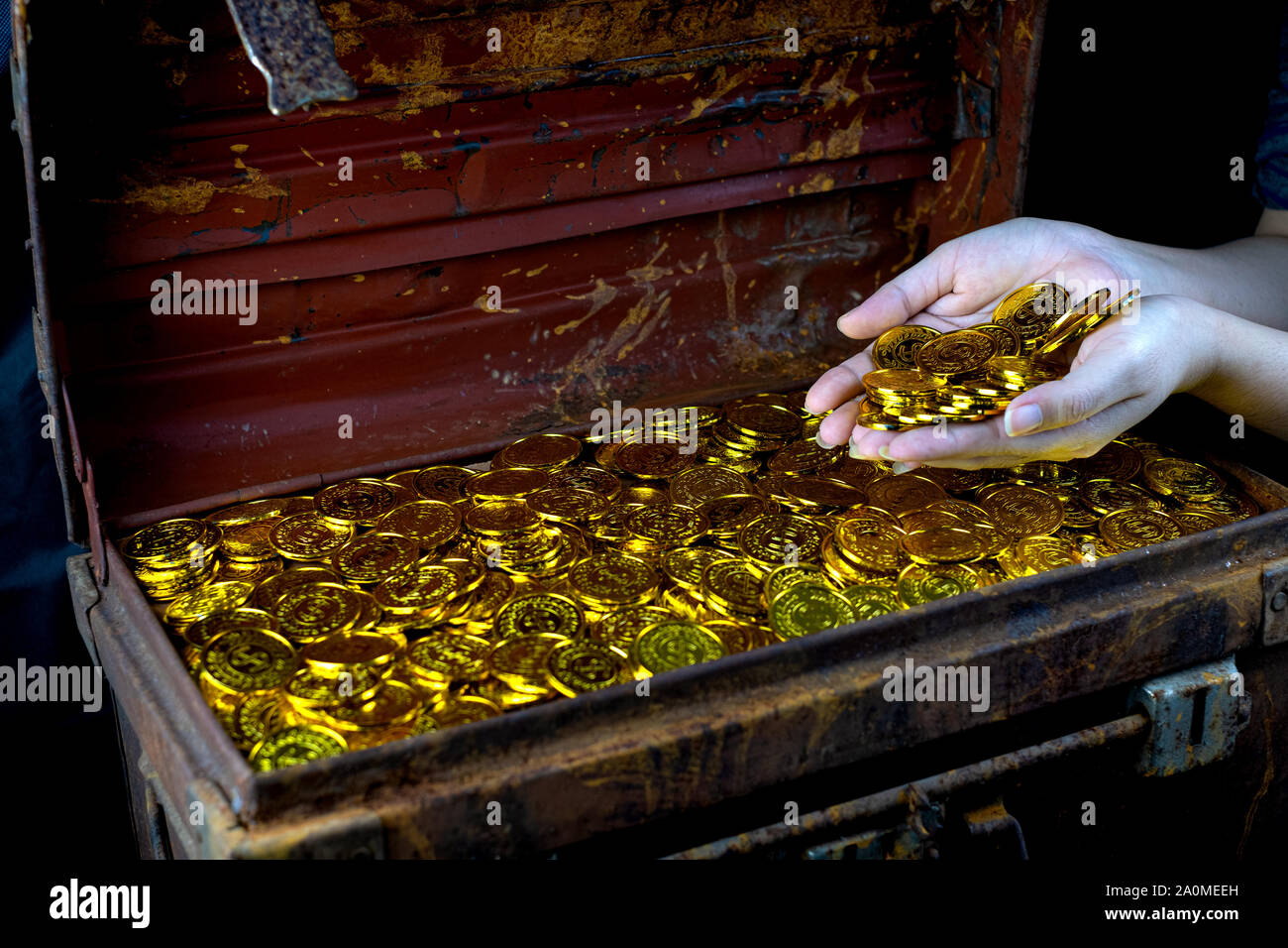 Lots of stacking Gold Coin in lady hand and treasure chest at black