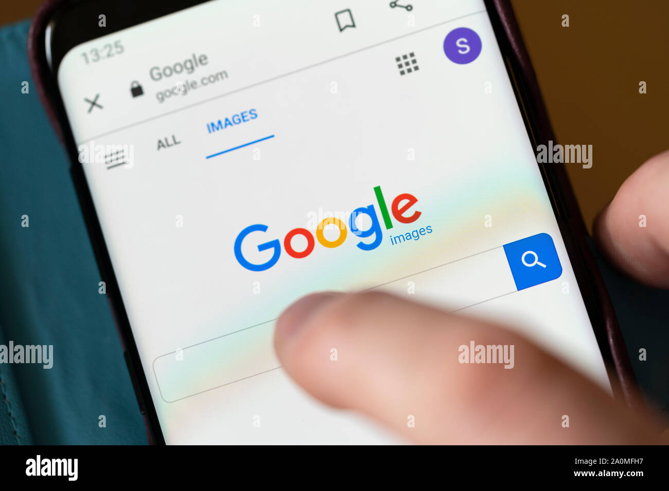A man about to search on a Google Images search bar on a smartphone Stock Photo
