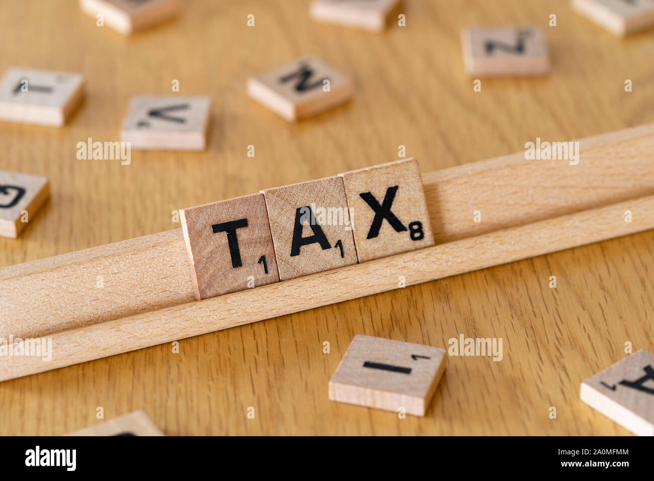 Wooden scrabble letters on a rack spelling out the word Tax Stock Photo