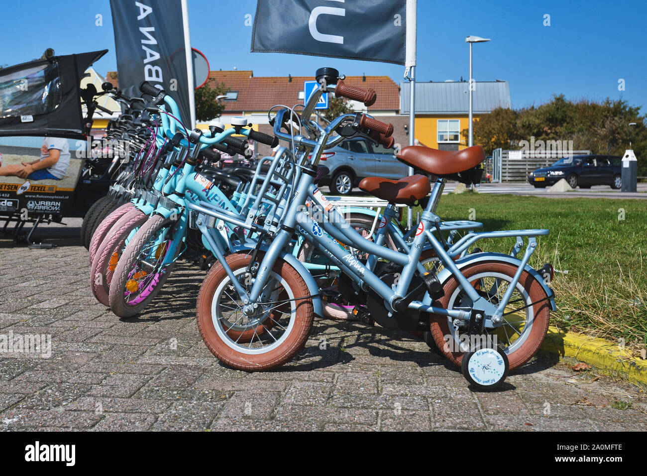 De Koog, Texel / Netherlands - August 2019: Small blue bicycles with training wheels for children at bike renting station for tourists on island Texel Stock Photo