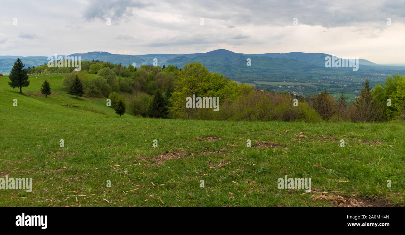 springtime Slezske and Moravskoslezske Beskydy mountains scenery with meadows, trees and hills from place named Dziol above Hradek village in Czech re Stock Photo