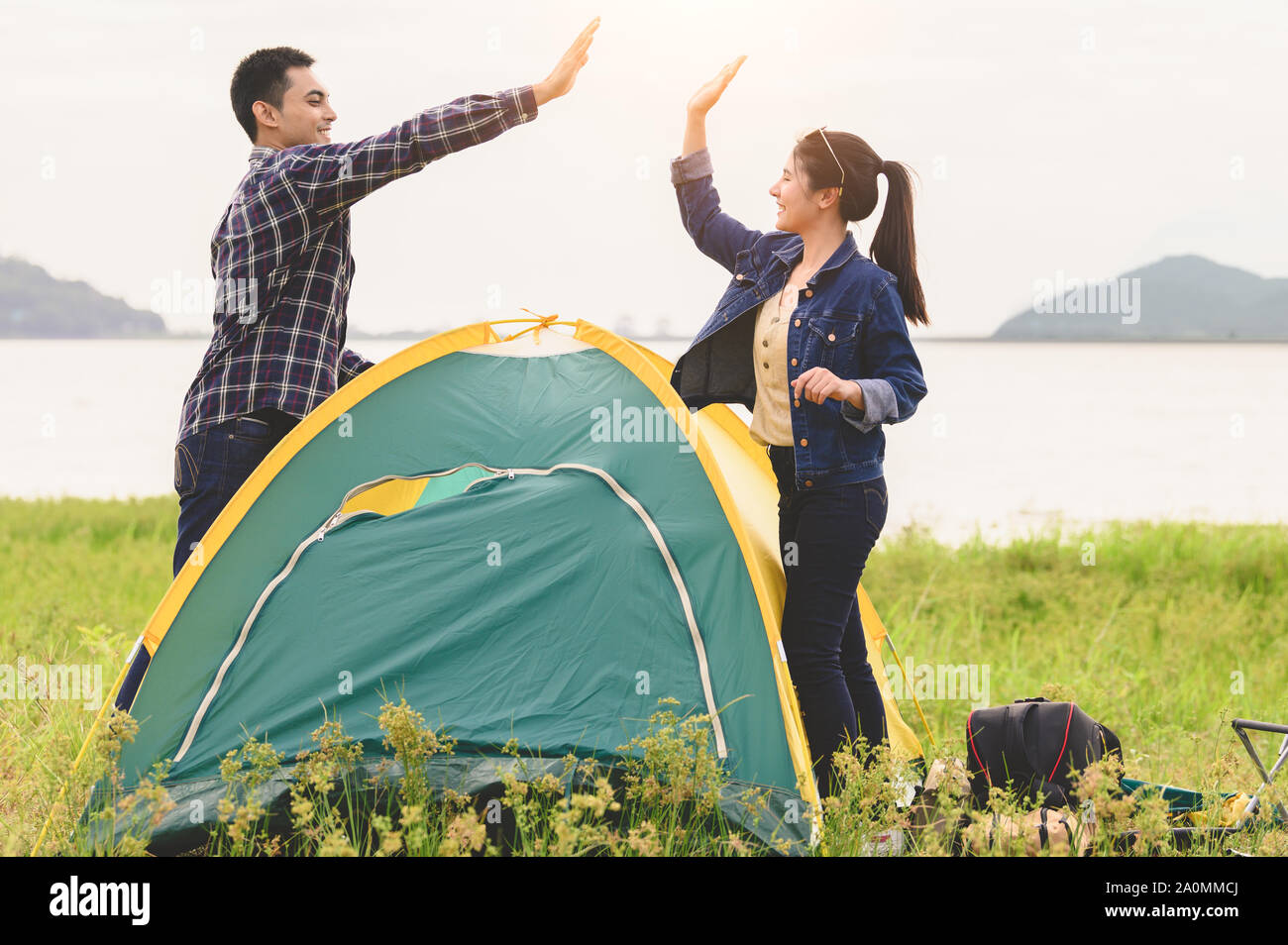 Two Asian couples finished pitch and doing high five for stay in camping tent  meadow overnight honeymoon picnic. People lifestyle and Valentine day l Stock Photo