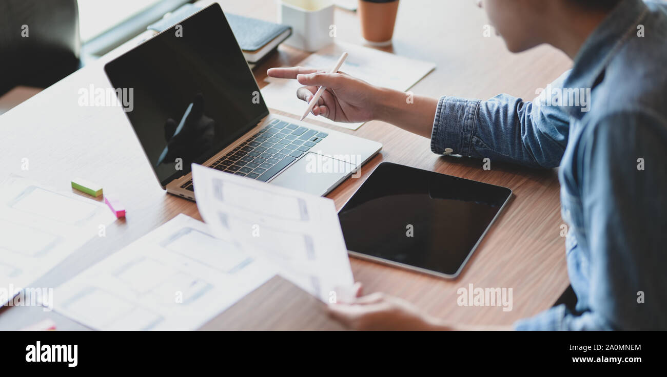 Close-up view of UX web developer working on his project about UX template while using laptop computer and tablet Stock Photo