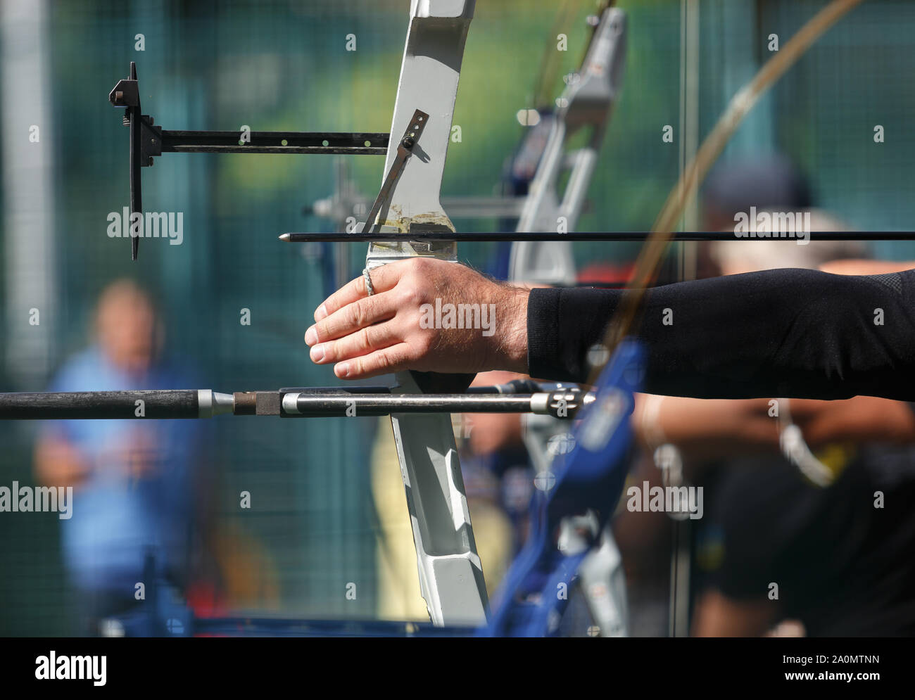 Group of professional archers shooting targets with modern longbows.Focus on athlete holding bow with arrow.Olympic archer competition outdoor Stock Photo