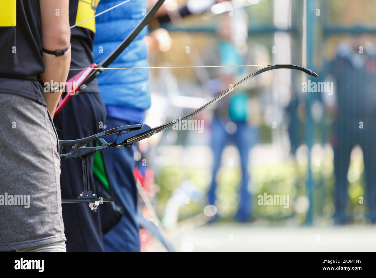Longbow archer holds modern sport bow with arrow on outdoor sport competition.Professional olympic archers training in shooting targets with bows and Stock Photo