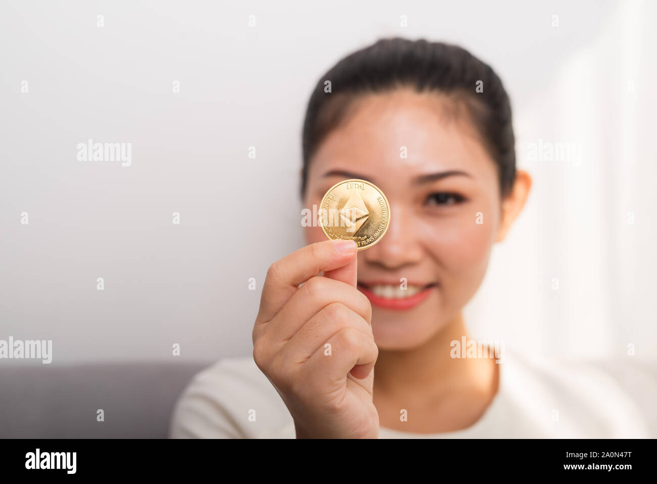 Asian woman gets big money! Attractive woman with holds bitcoin in hands and looks into the camera. Stock Photo