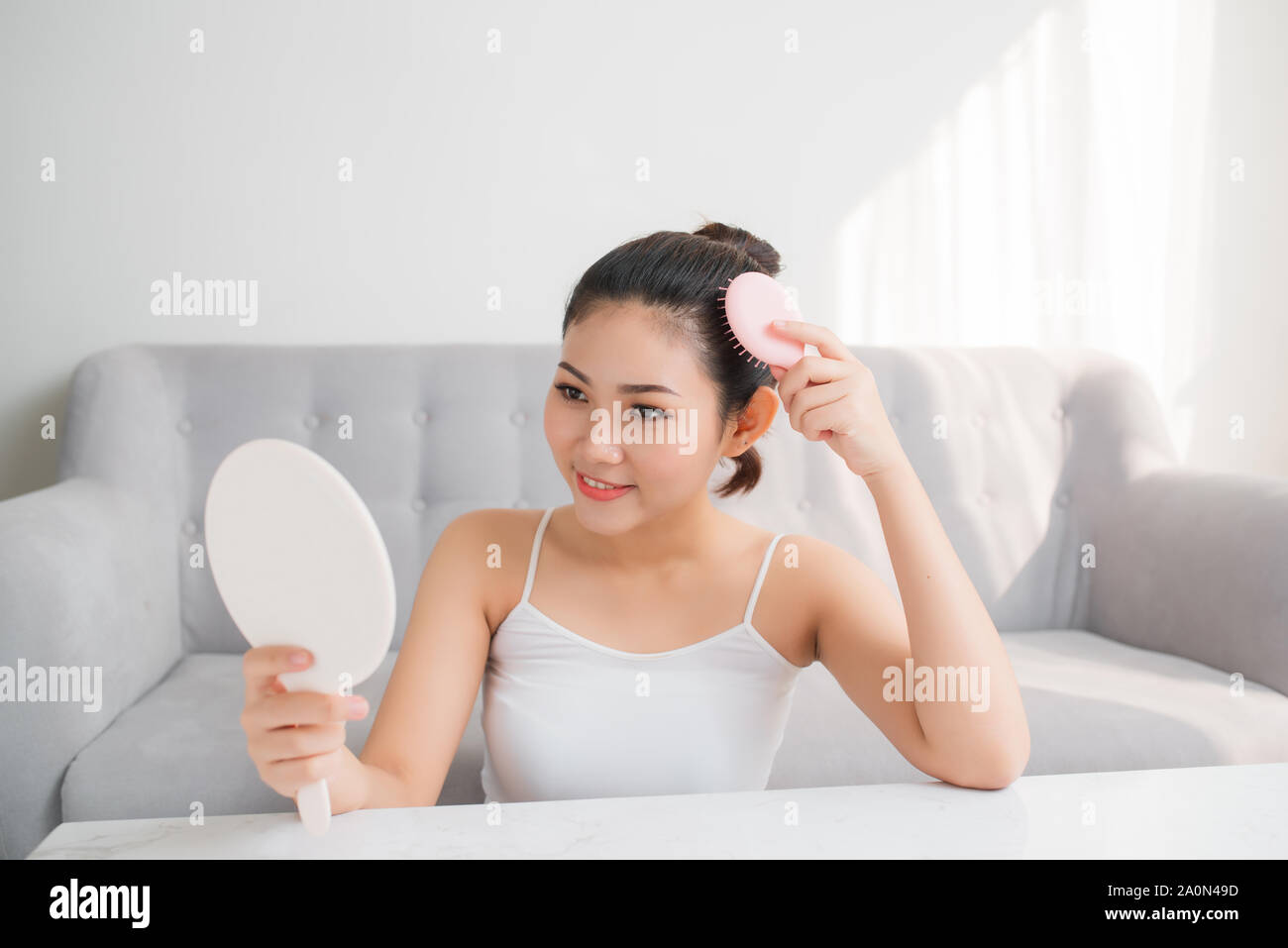 Young Asian woman combing hair and looking in mirror Stock Photo