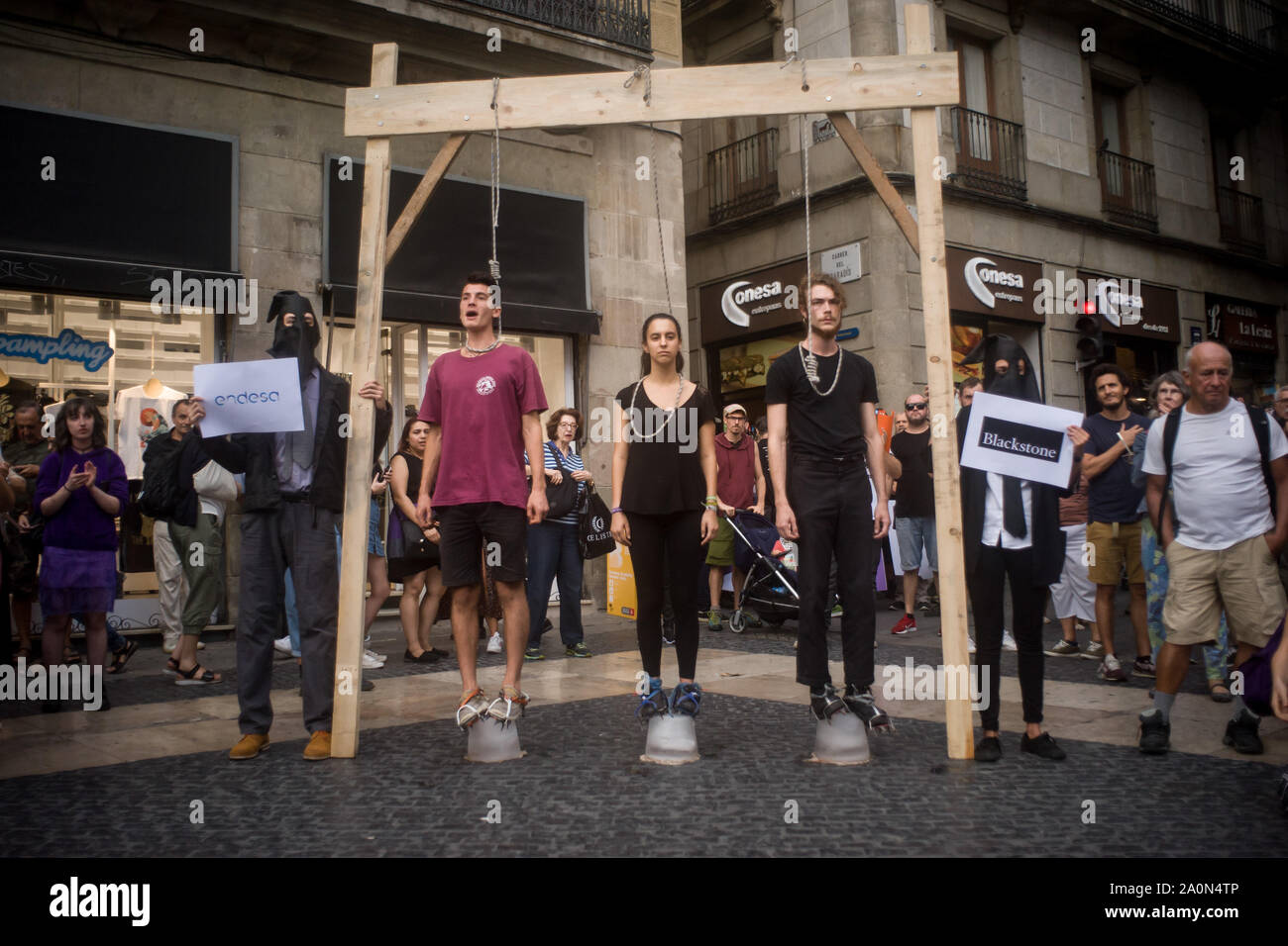 Three demonstrators stand under a gallows with a rope around their ...