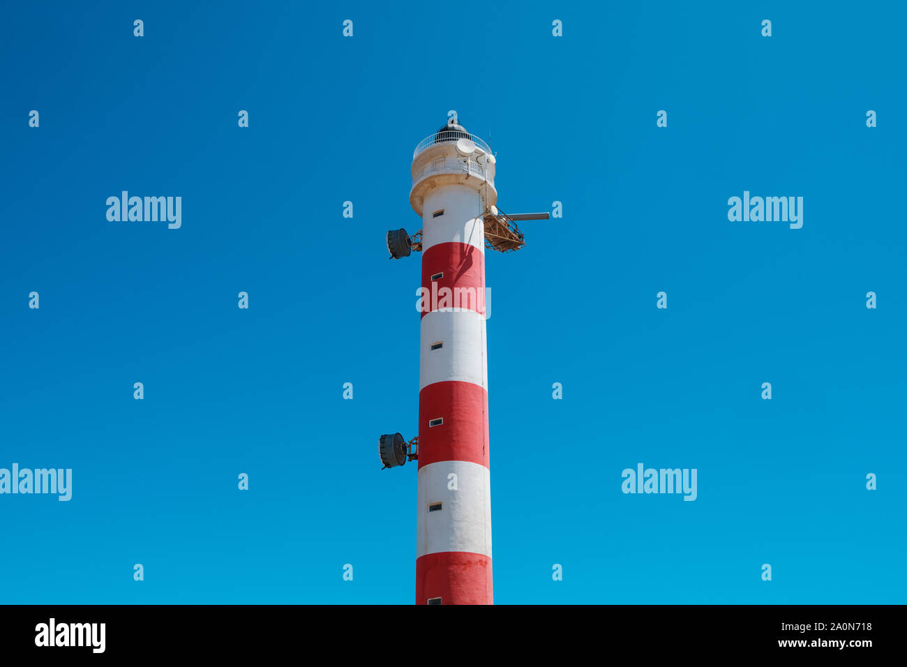 red,white lighthouse tower isolated on blue sky Stock Photo