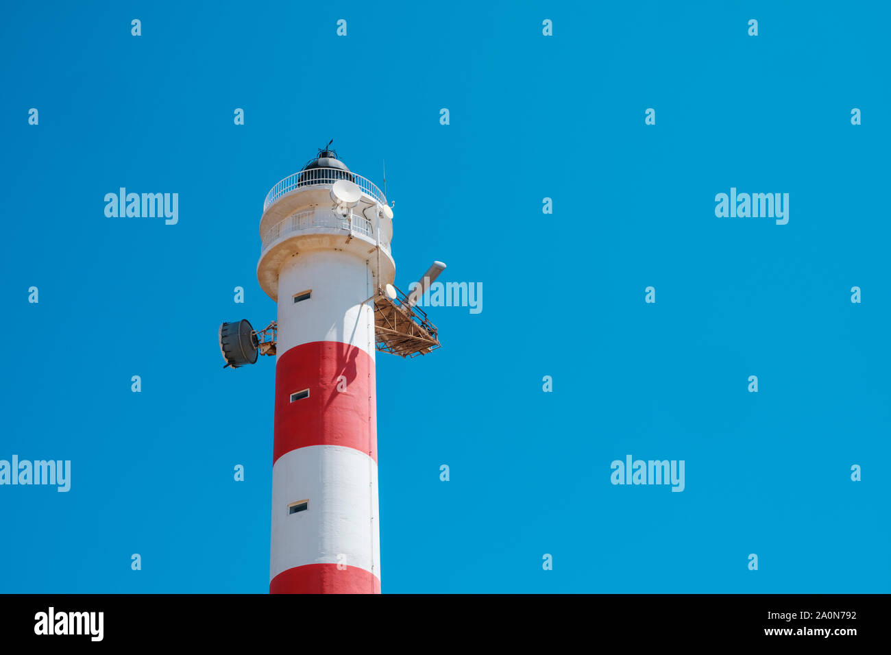 red,white lighthouse tower isolated on blue sky Stock Photo