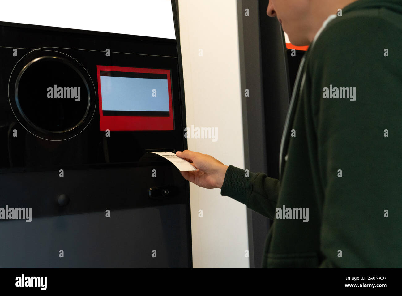 Man uses a self service machine to receive used plastic bottles and cans in a store Stock Photo