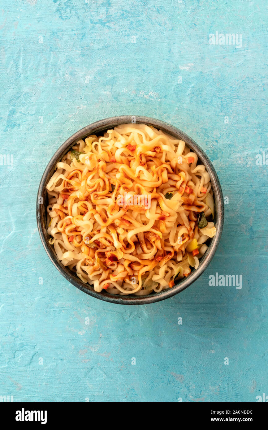 Instant soba noodles with carrot and a sauce, overhead shot on a teal