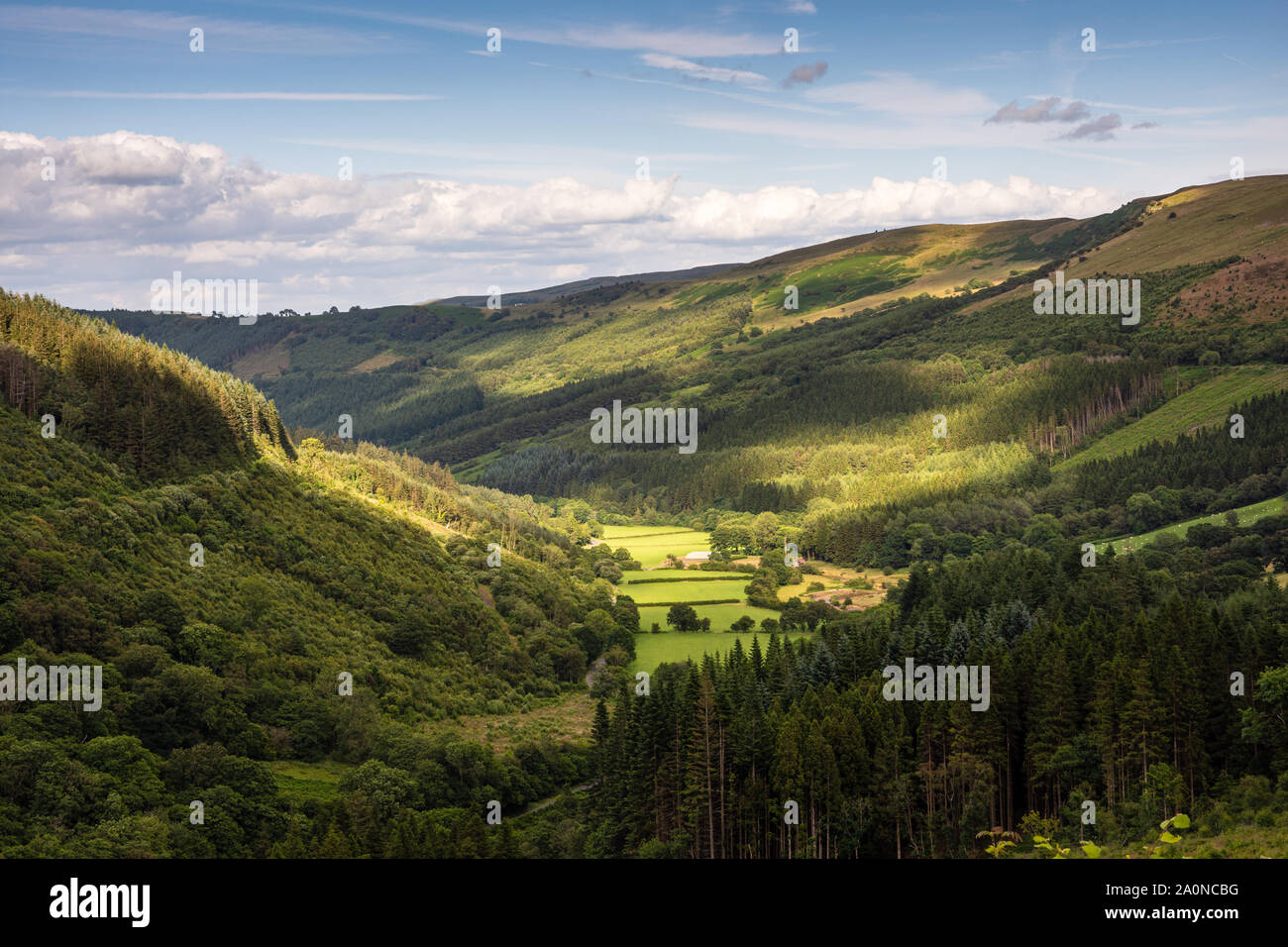 Patches of sunlight fall on the fields and forests of Glyn Collwyn valley under the Brecon Beacons mountains of South Wales. Stock Photo