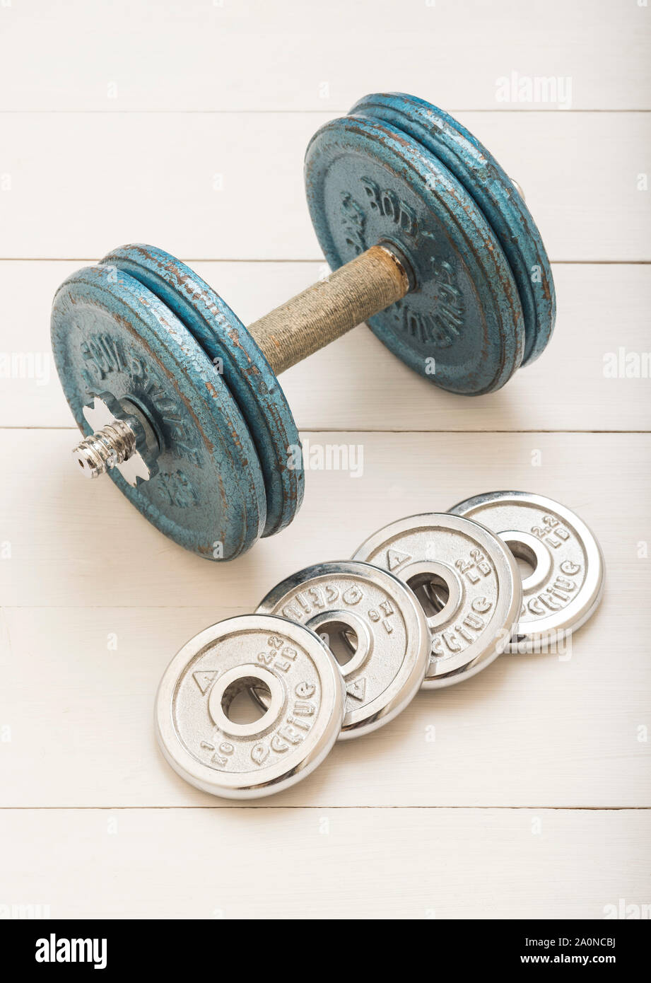 A dumbbell and weights on a white boarded background Stock Photo Alamy
