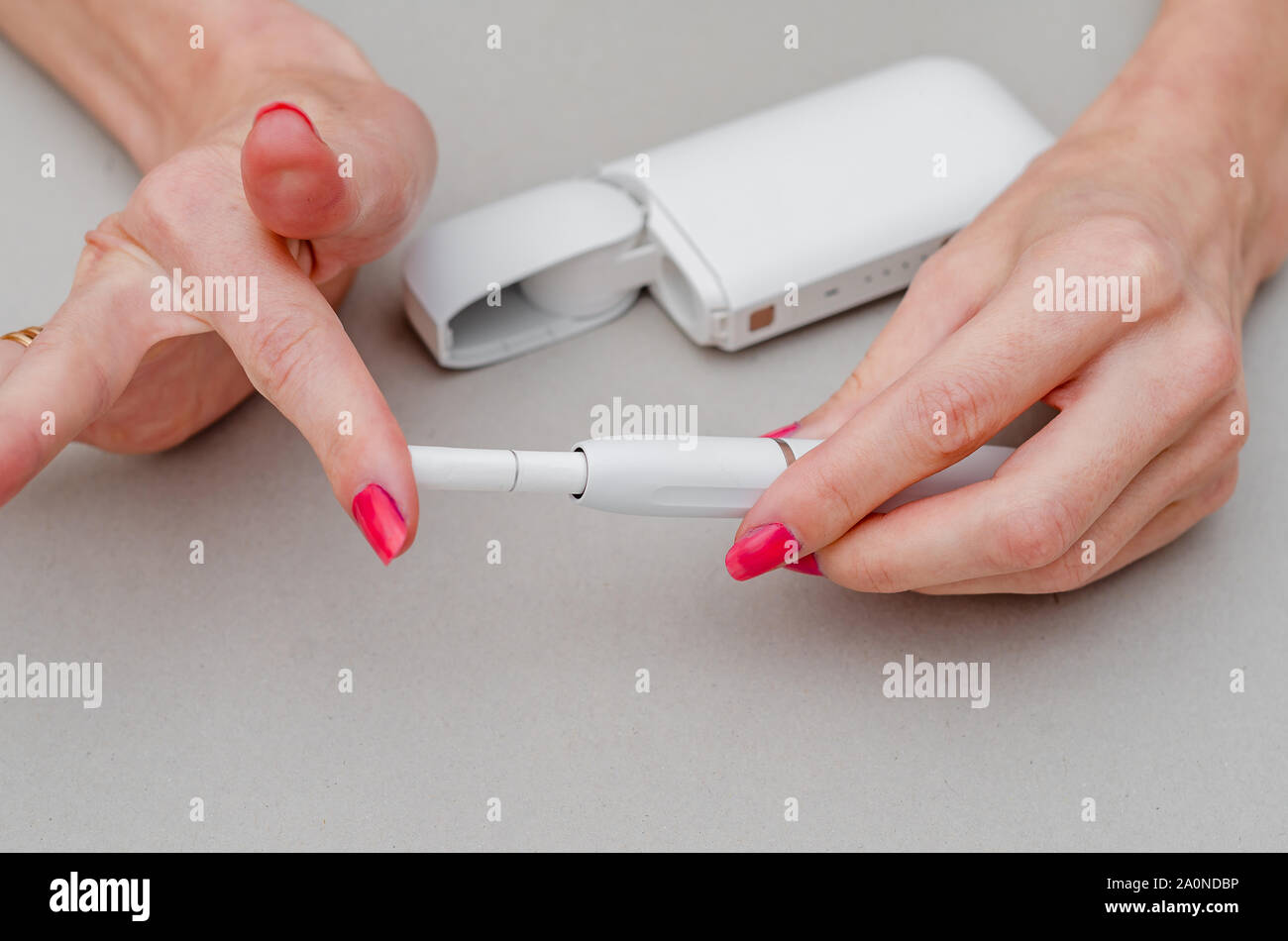 Woman's hands holds an electronic cigarette. Insert a cigarette into the  mouthpiece. Smoking, health, struggle, addiction Stock Photo