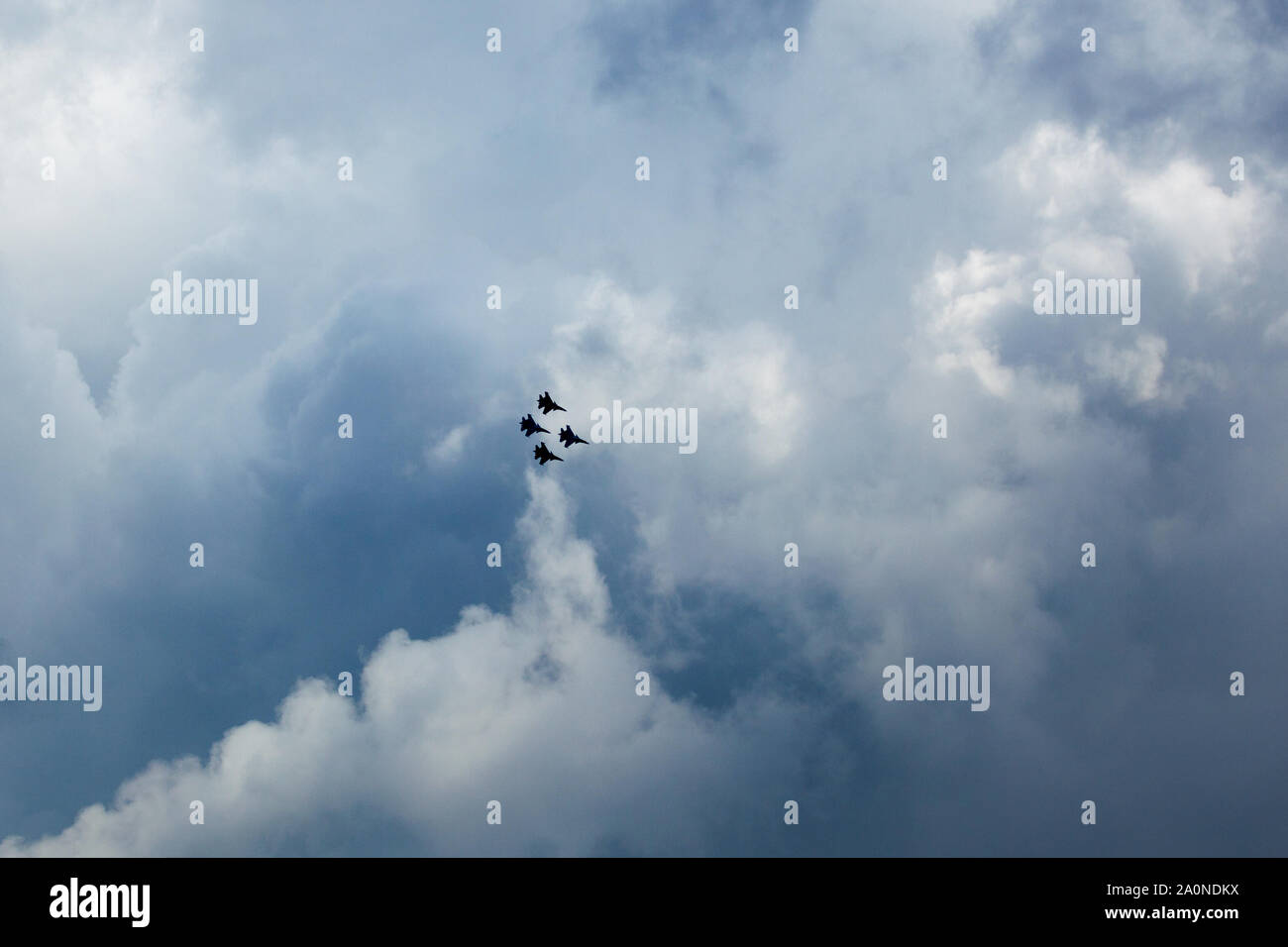 Silhouettes of four Su-30 SM, russian fighter aircrafts high in the blue cloudy sky Stock Photo