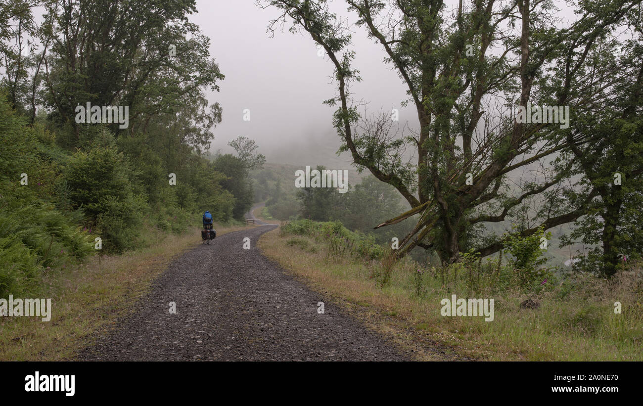 A touring cyclist rides through the Brecon Beacons on the former Brecon and Merthyr Railway line, now part of the National Cycle Network route 8. Stock Photo