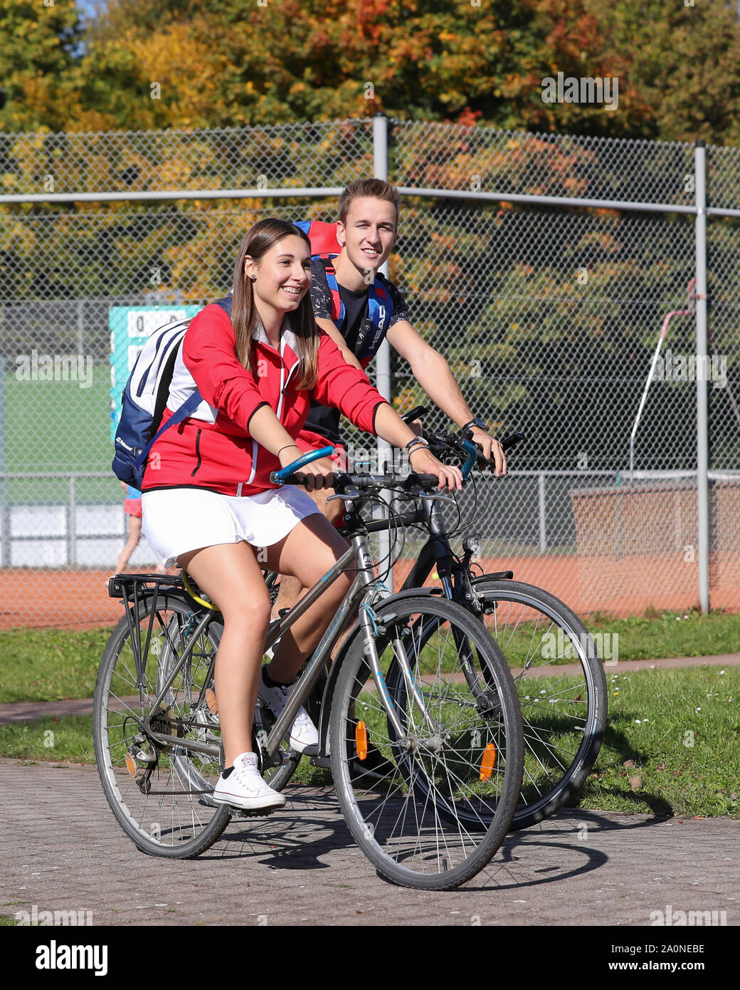 Young couple cycling between the courts in tennis club Stock Photo - Alamy