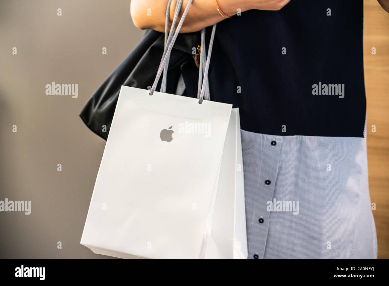 A female customer carries an Apple shopping bag at an Apple retail