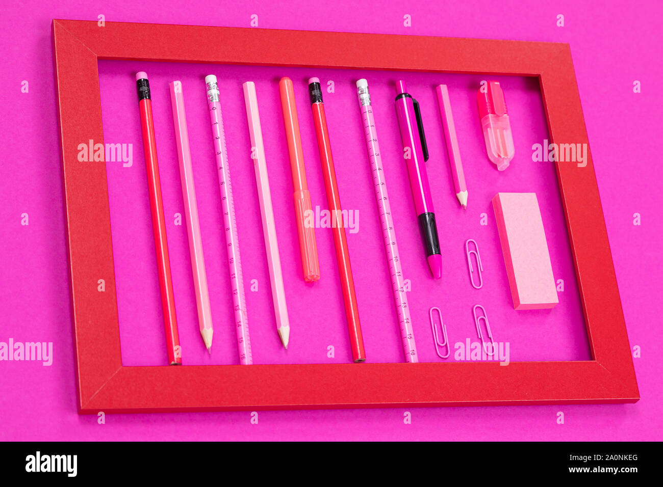 Straightly arranged group of pink color office incidentals in red frame on pink surface cutout Stock Photo