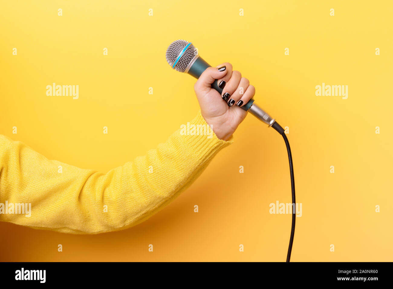 hand holding microphone over yellow background Stock Photo - Alamy