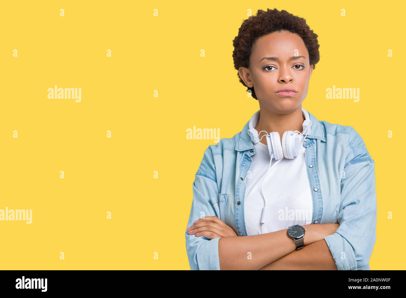 Young african american woman wearing headphones over isolated background skeptic and nervous, disapproving expression on face with crossed arms. Negat Stock Photo