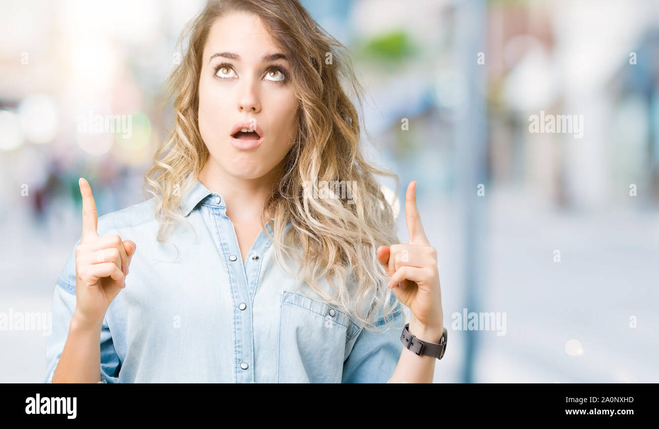 Beautiful young blonde woman over isolated background amazed and ...