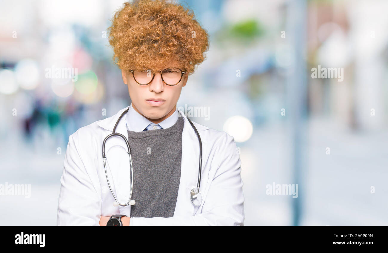 Young handsome doctor man wearing medical coat skeptic and nervous