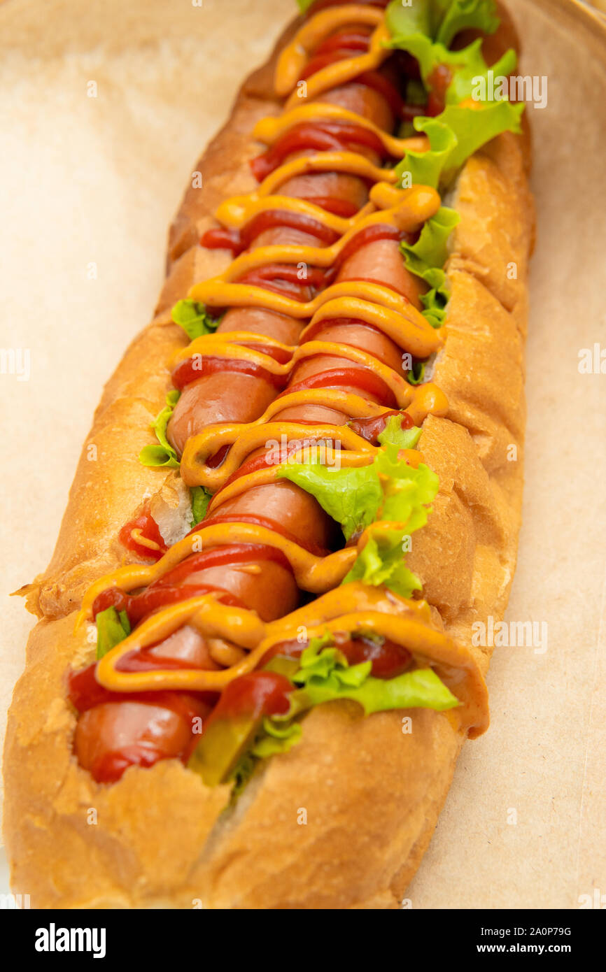 Hot dog with salad and cucumbers with tomato ketchup and mustard on