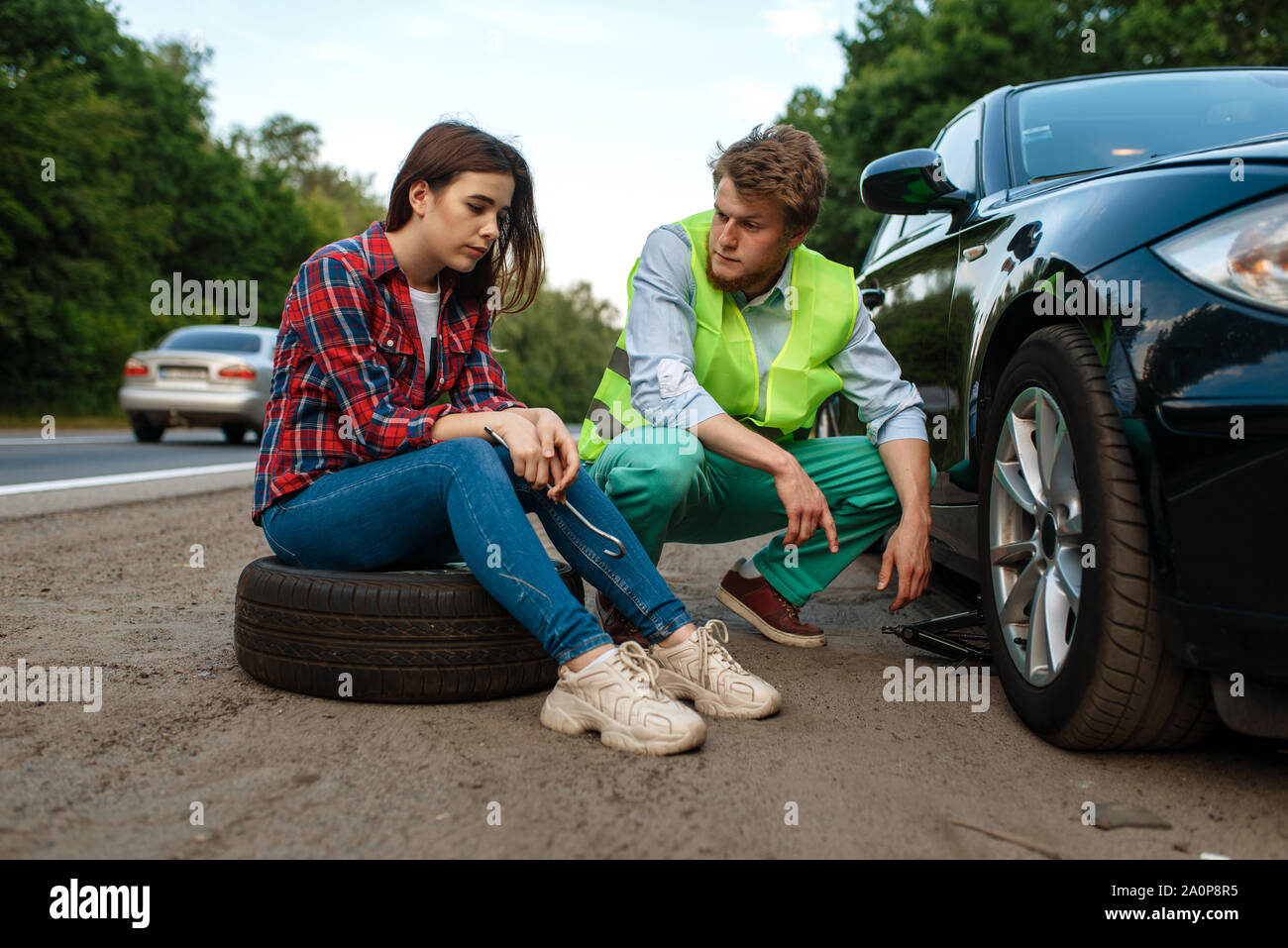 Young couple repair flat tyre, car breakdown Stock Photo