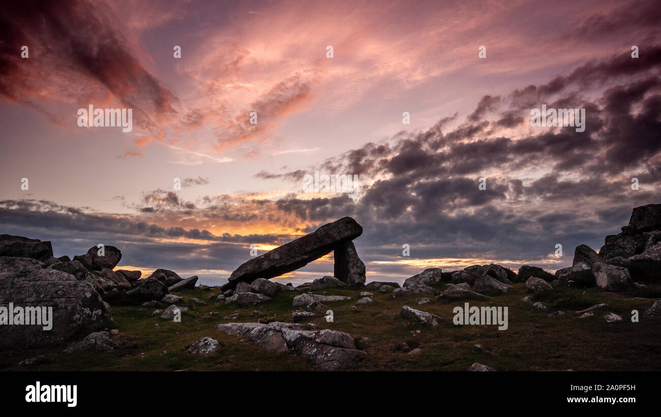 The sun sets over St David's Head in Pembrokeshire National Park, silhouetting the neolithic burial chamber of Arthur's Quoit. Stock Photo