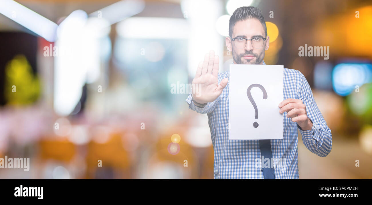 Handsome young business man holding paper with question mark over