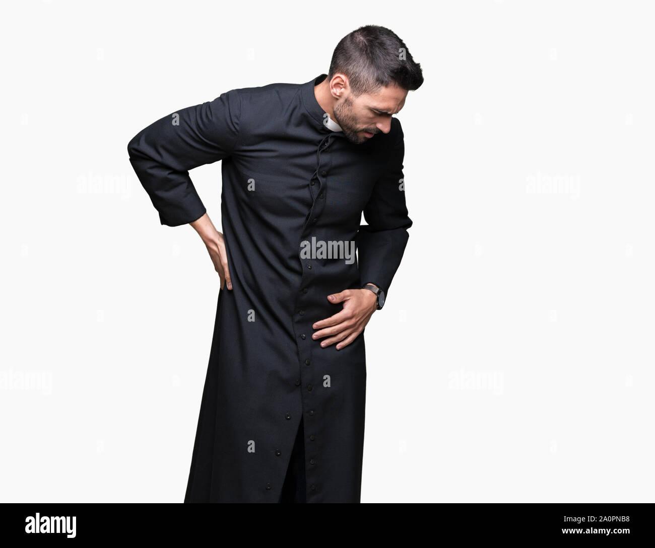 Young Christian priest over isolated background Suffering of backache, touching back with hand, muscular pain Stock Photo