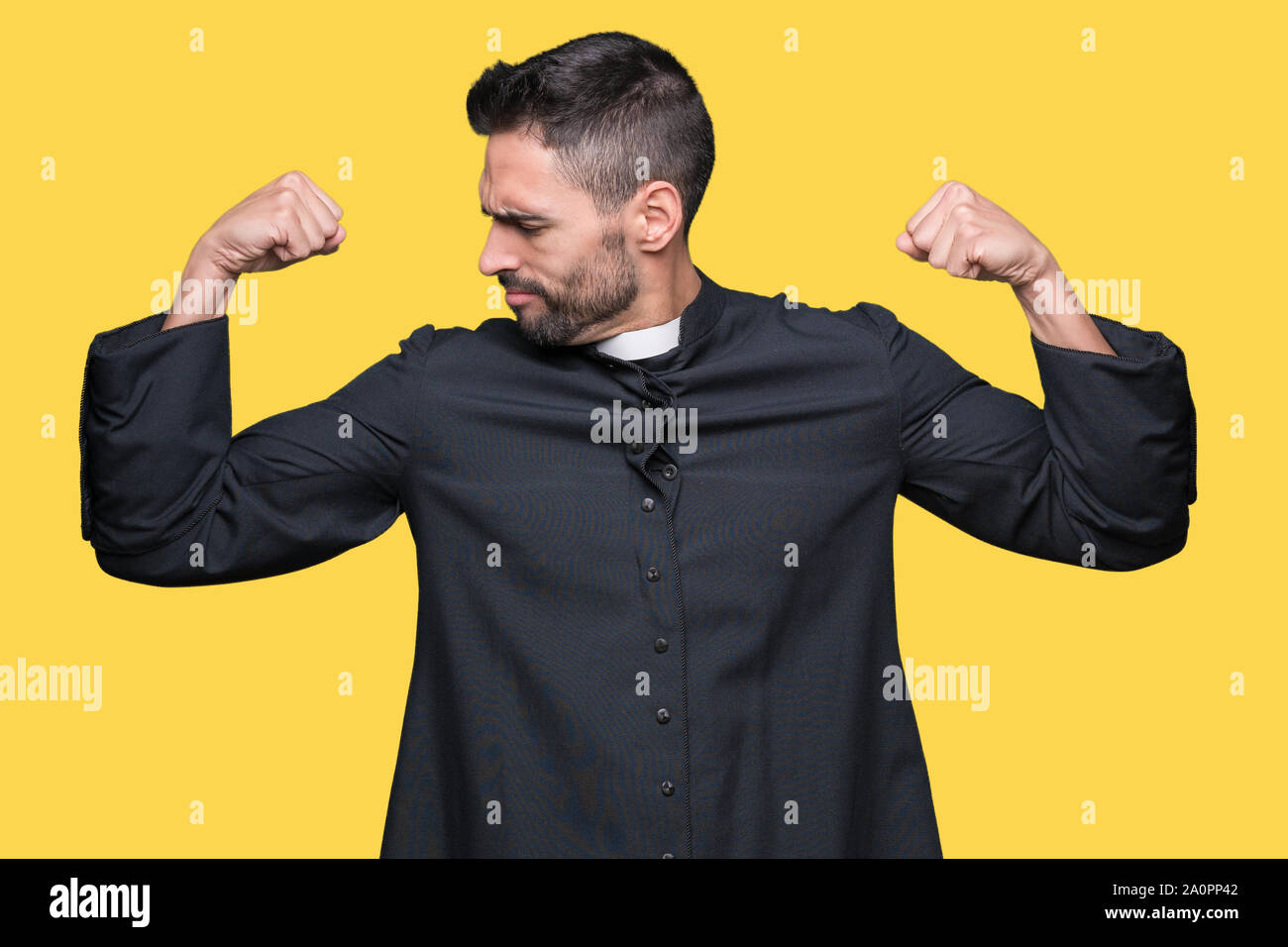 Young Christian priest over isolated background showing arms muscles smiling proud. Fitness concept. Stock Photo