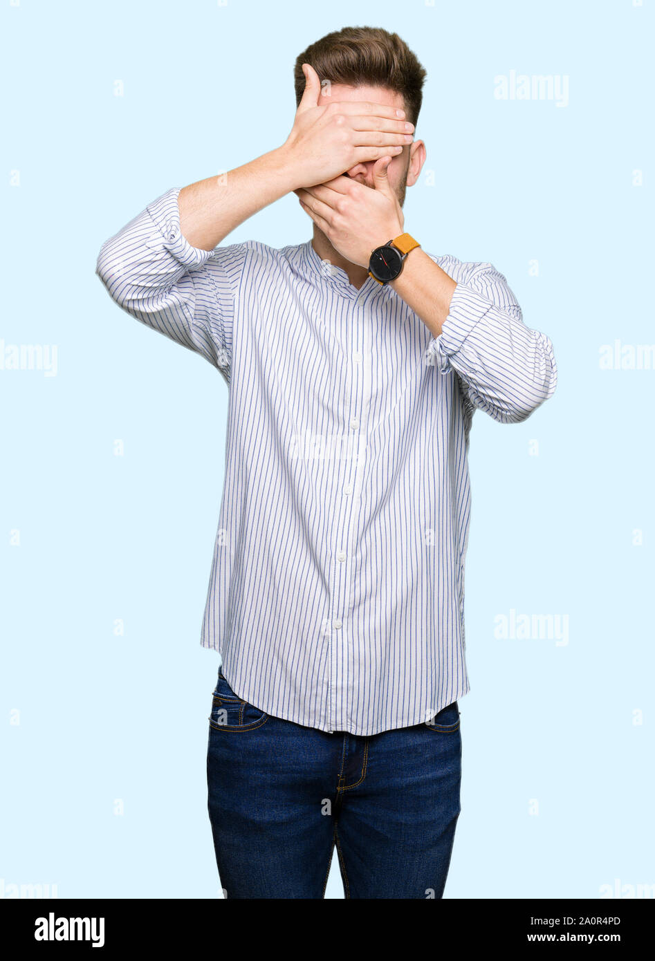 Young handsome man Covering eyes and mouth with hands, surprised and ...